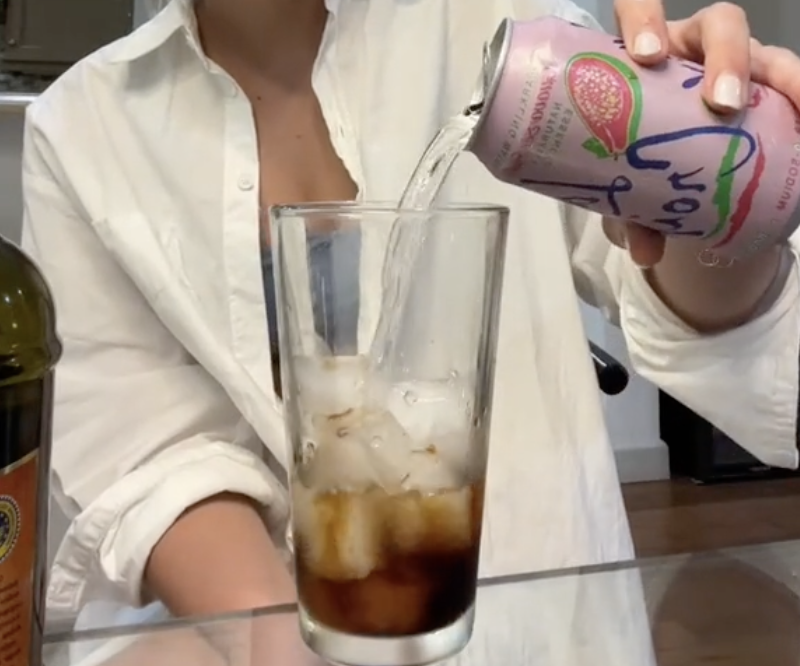 Woman in a TikTok video pouring balsamic LaCroix into a glass filled with ice